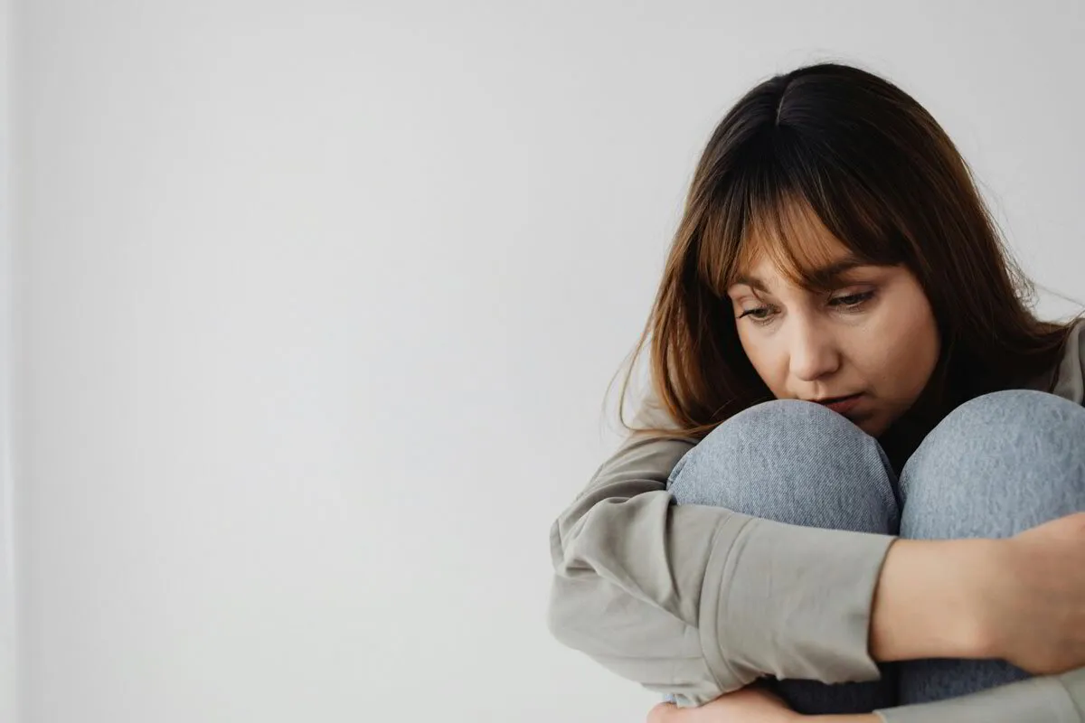 Woman anxiously sitting holding her knees