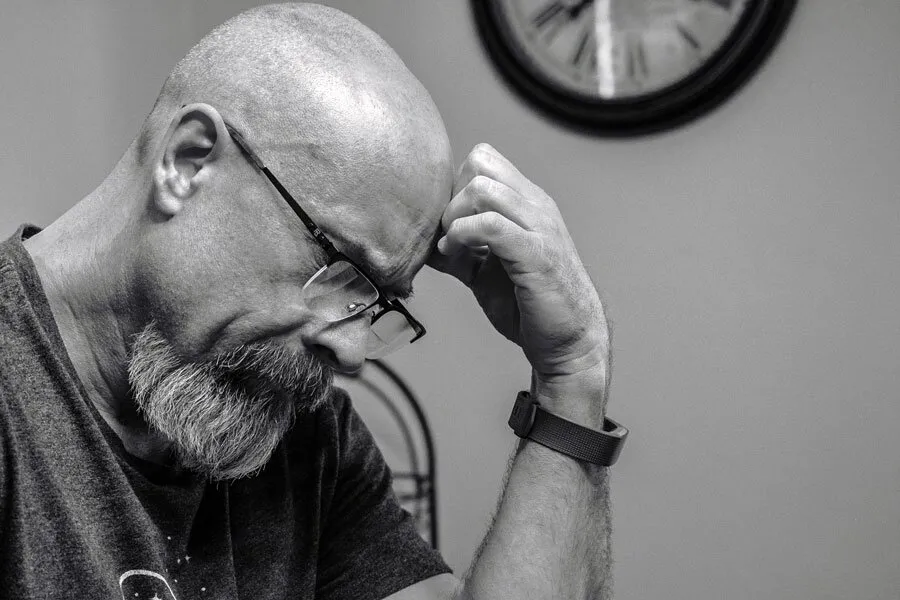 Stressed man frowning hand on his head